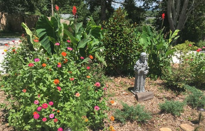 St Francis statue surrounded by garden plantings in the entrance drive of St Francis Cottage